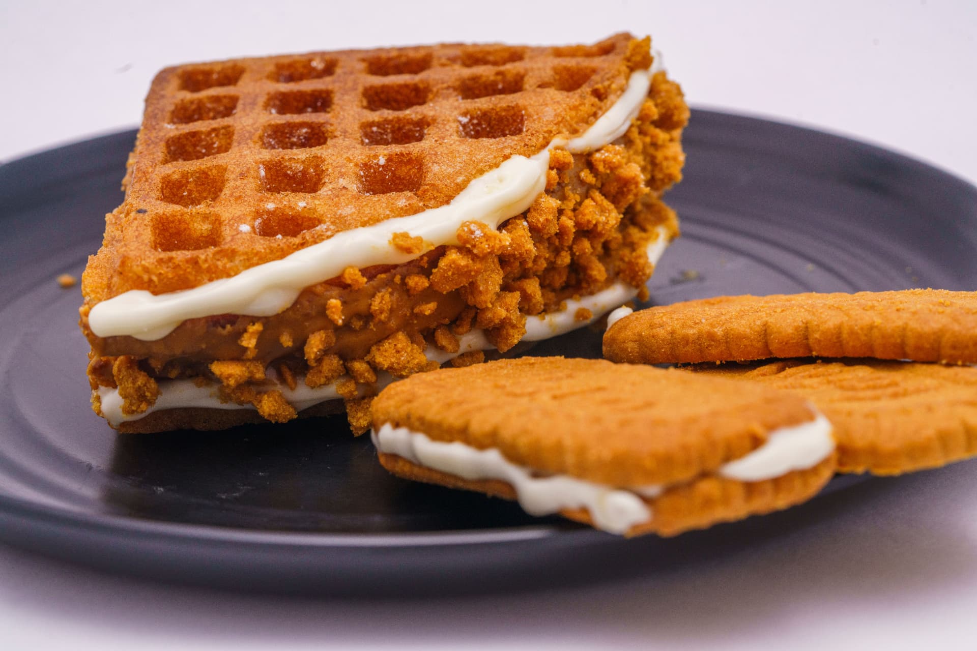 Waffle sandwich beside biscuits on a dark plate