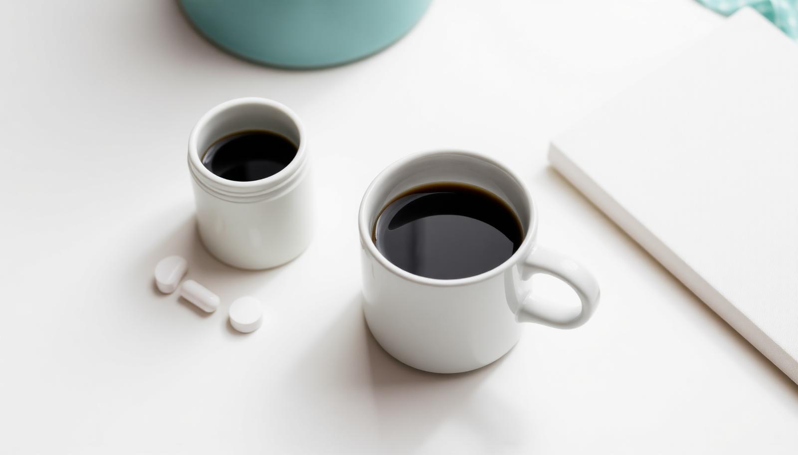 A coffee cup on a desk next to a laptop